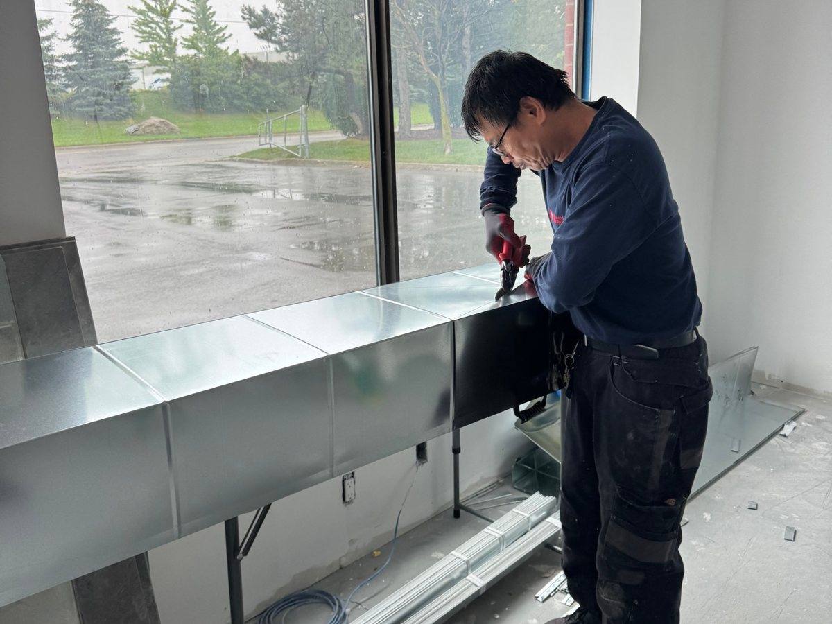 Franklin Heat & Cool technician cutting new sheet metal ductwork in a commercial unit
