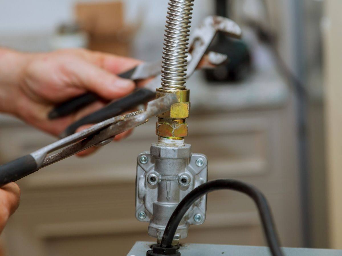 Technician tightening a flexible gas line connection on a gas valve