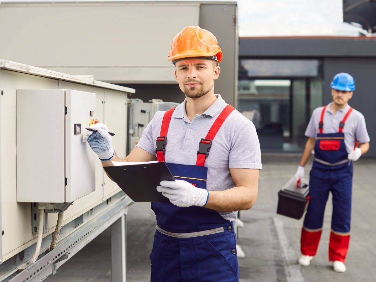HVAC technician with a clipboard inspecting commercial rooftop equipment